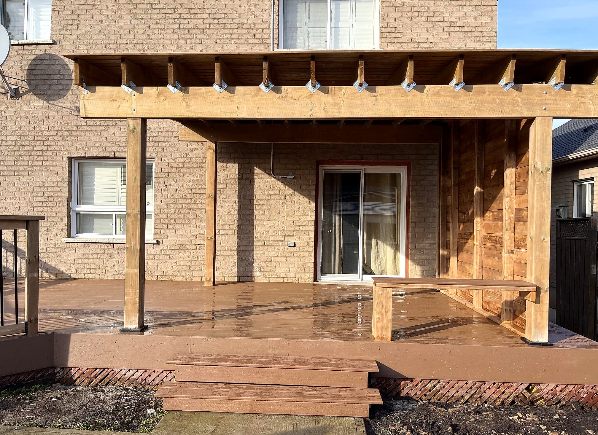 Covered deck built by Global Construction Homes in composite board with timber posts, a built-in bench and a cedar privacy wall