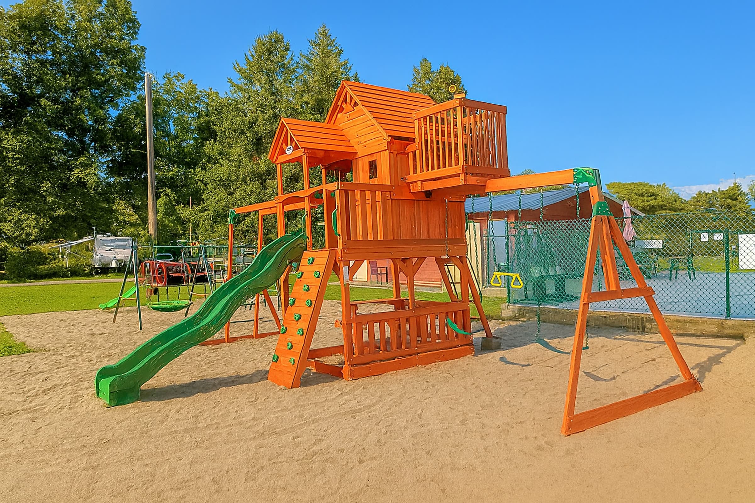 Three-quarter view of a cedar play structure showing the lookout deck, monkey bars and swing beam
