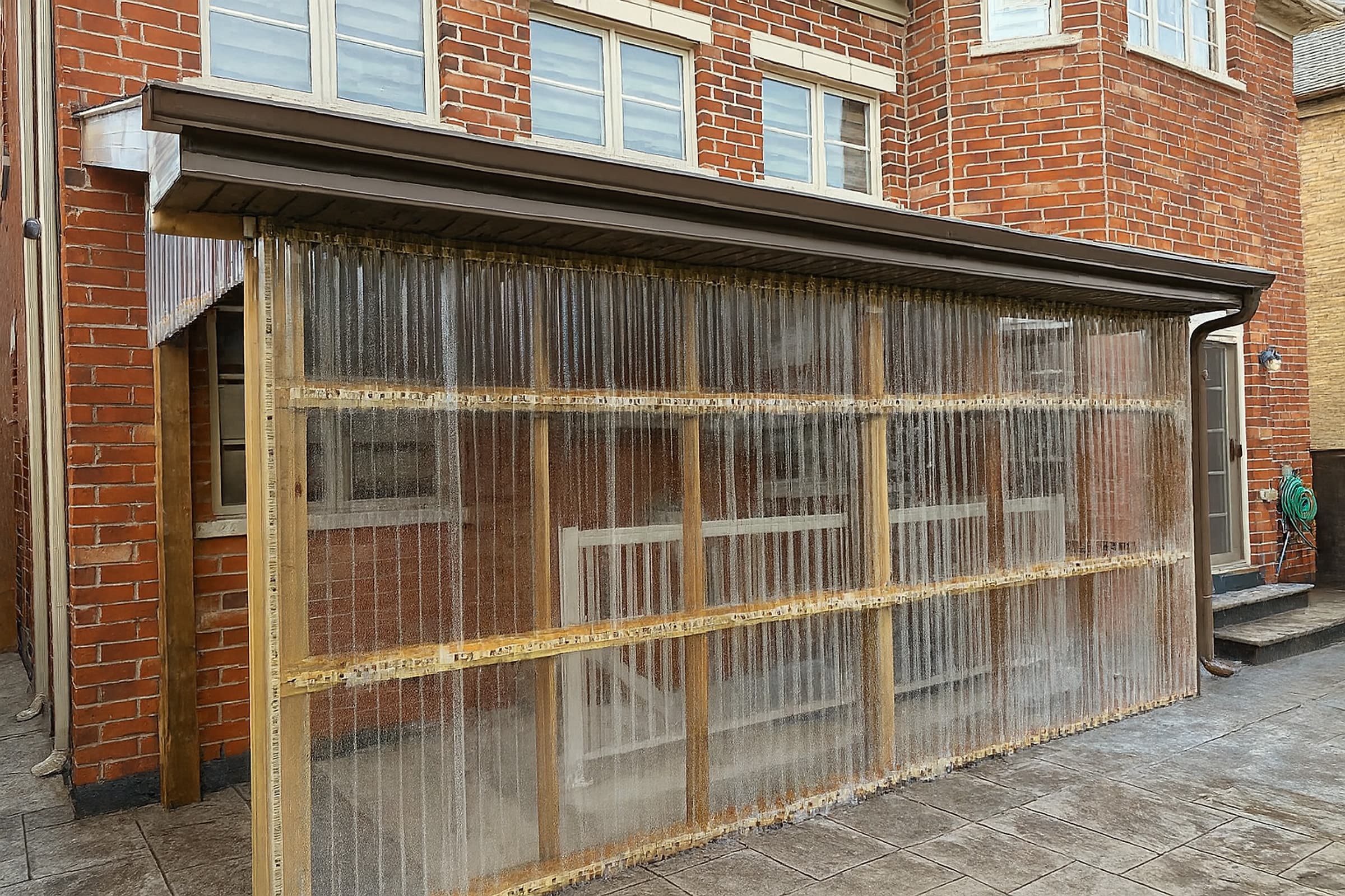 Side elevation of a rear porch enclosure with clear corrugated polycarbonate panels on a timber frame