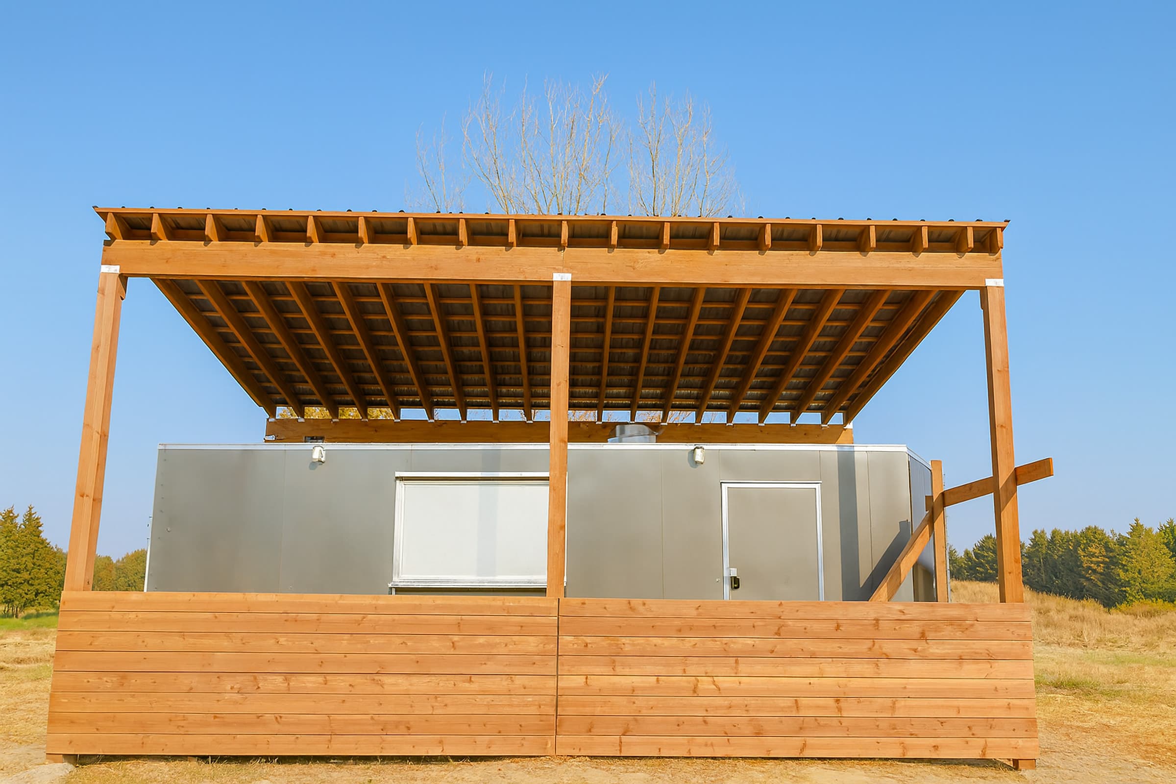 Free-standing timber canopy with exposed rafters and a horizontal timber screen wall built over a service unit